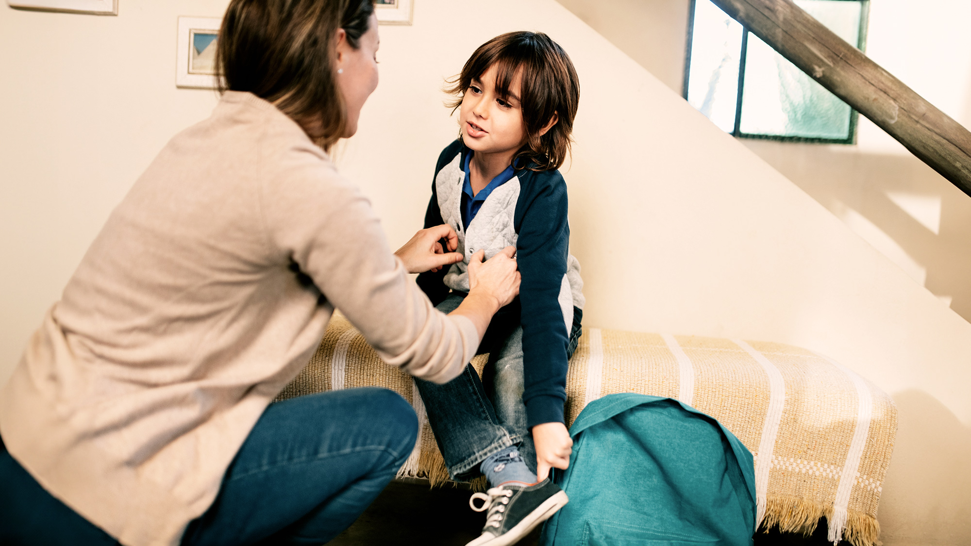 A mom helping her son get dress for school