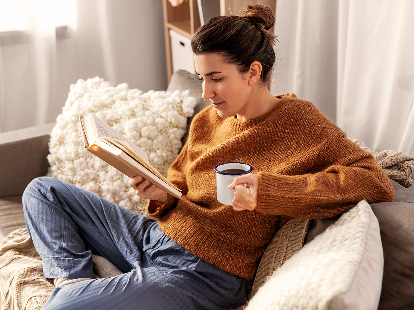 Une femme qui lit un livre avec un café à la main